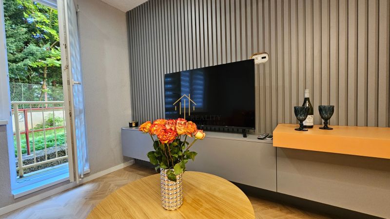 Living room in a two-room apartment with a wooden decor floor and a view of the garden.
