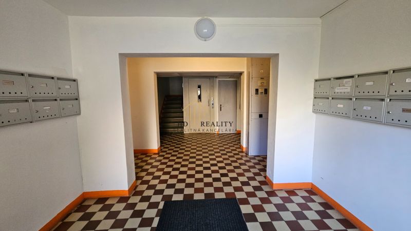 The entrance hall of an apartment building with numerous mailboxes and a checkered floor.