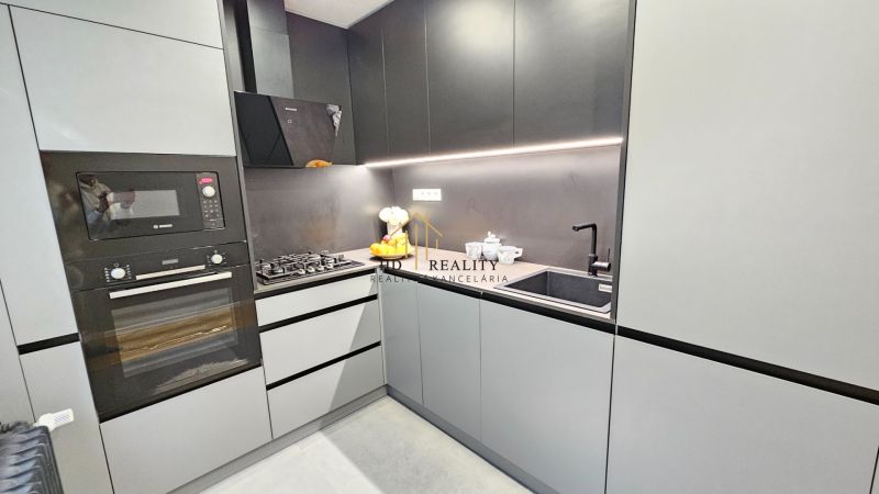 A kitchen in a 2-room apartment with modern appliances and sleek cabinets.