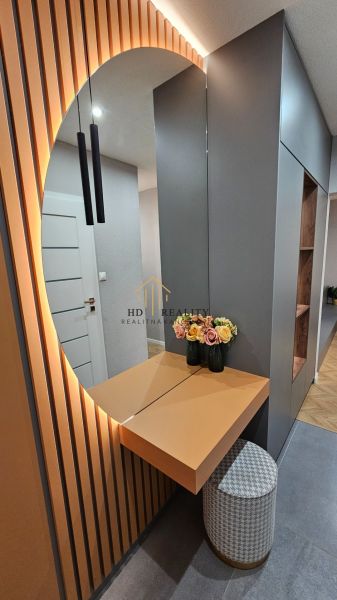 Entrance hallway in a 2-room apartment with a decorative mirror, flowers, and lighting.