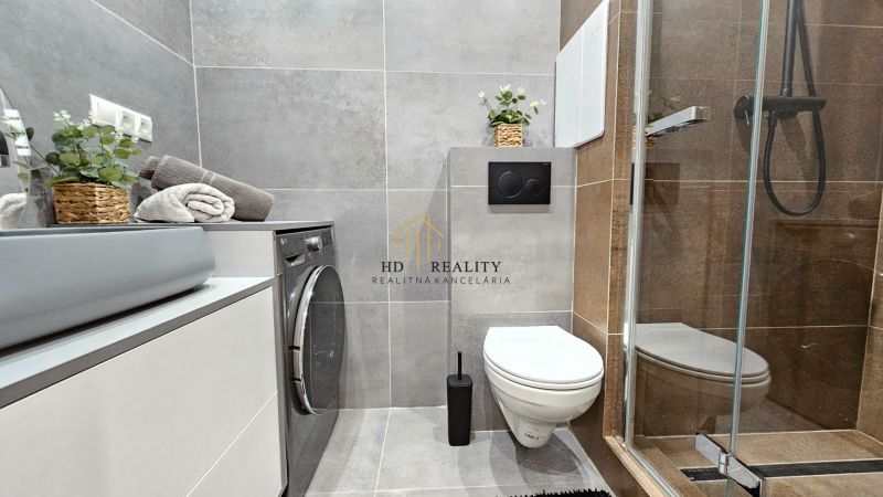 A modern bathroom in a 2-room apartment with a shower, sink, toilet, and washing machine.