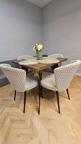 Dining table with four chairs and a wooden-patterned floor in a two-room apartment.