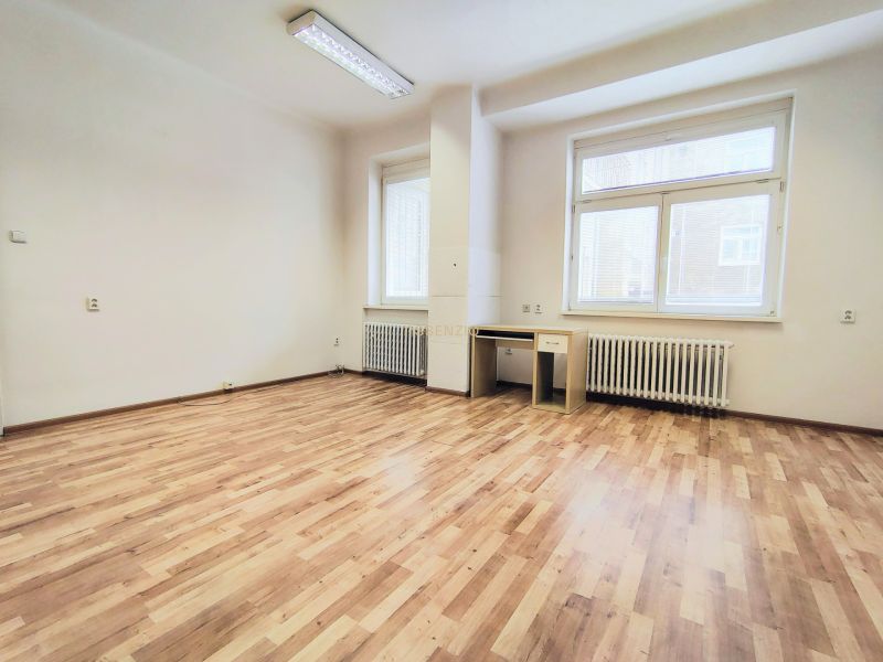 Bright office with wood-patterned flooring, a desk, and white walls.