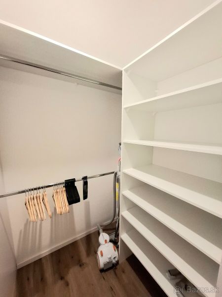 A wardrobe with a shelving system and a hanger holder in a 2-room apartment with a wooden decor floor.