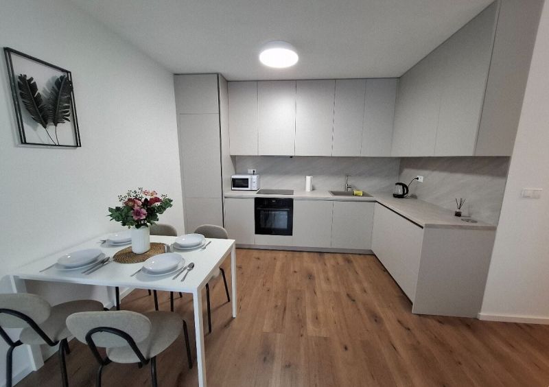 A kitchen in a 2-room apartment with a set table and a floor with a wooden decor.