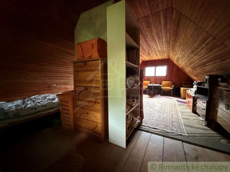 Attic room with wooden paneling, a wardrobe, and a floor with a wooden decor in a family house.