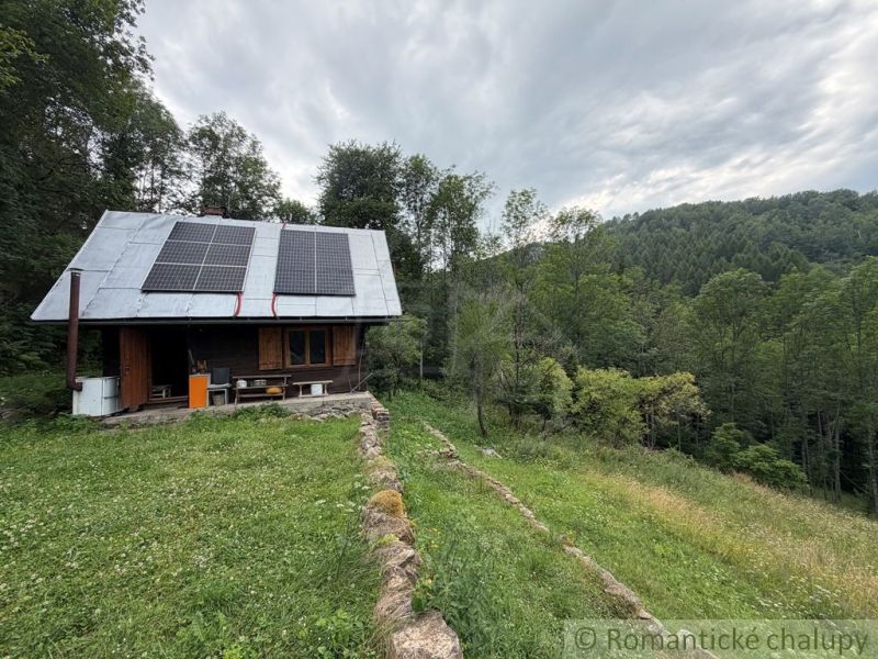 A family house in Kokava nad Rimavicou, with a lawn, solar panels, and surrounded by forest.