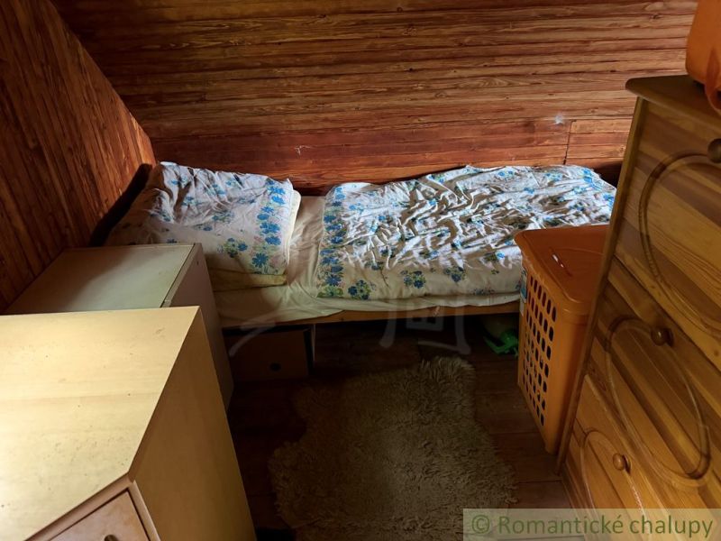 A bedroom in a family house with wooden walls, a bed, and a wardrobe.