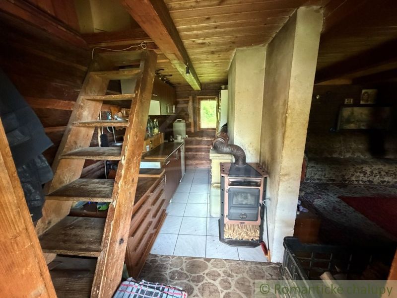 Interior of a family house with wooden stairs, a kitchen unit, and a tiled stove.