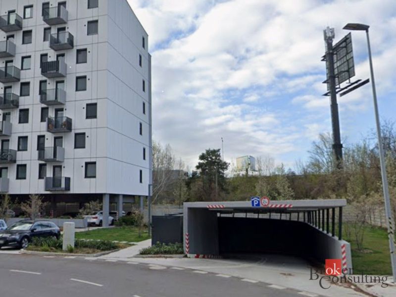 Parking on Hraničná Street in Bratislava-Ružinov in front of modern garages and an apartment building.
