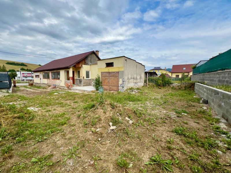 A family house in Ľubotín with a yard, nearby neighboring properties, with hills in the background.