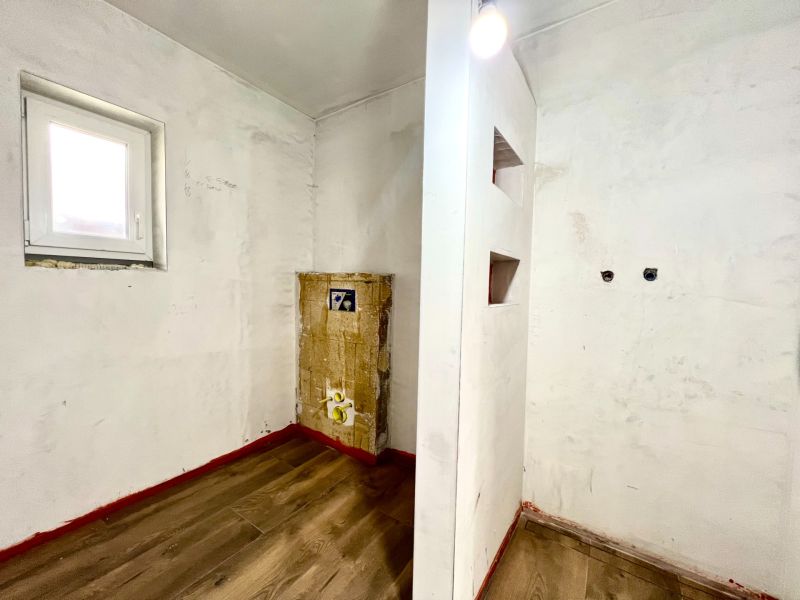 Interior of a family house with a wooden decor floor and a window on a white wall.