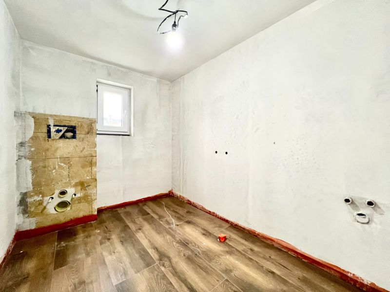 An empty room in a family house with a wooden decor floor and white walls.