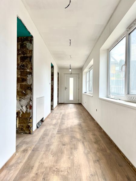 A hallway in a family house with a wooden decor floor and white walls.