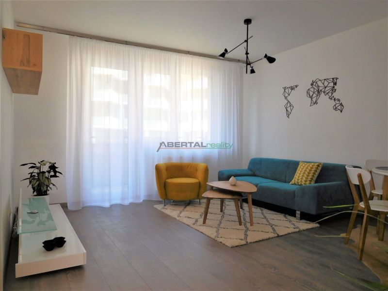 Living room in a two-room apartment with a wooden decor floor, a blue couch, and a yellow armchair.