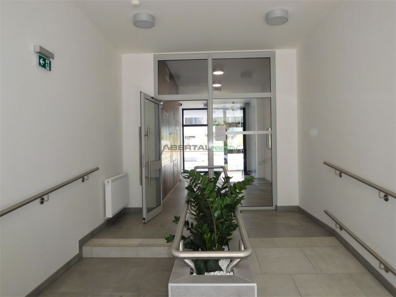 A hallway with tiles, railing, and flowers in a 2-room apartment.