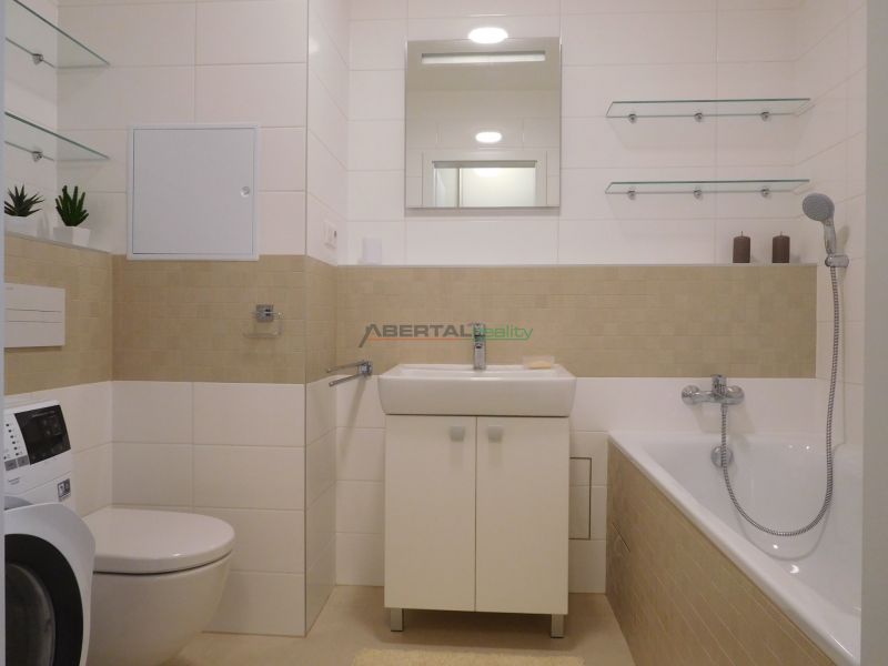 A bathroom in a 2-room apartment with a bathtub, sink, toilet, and washing machine.