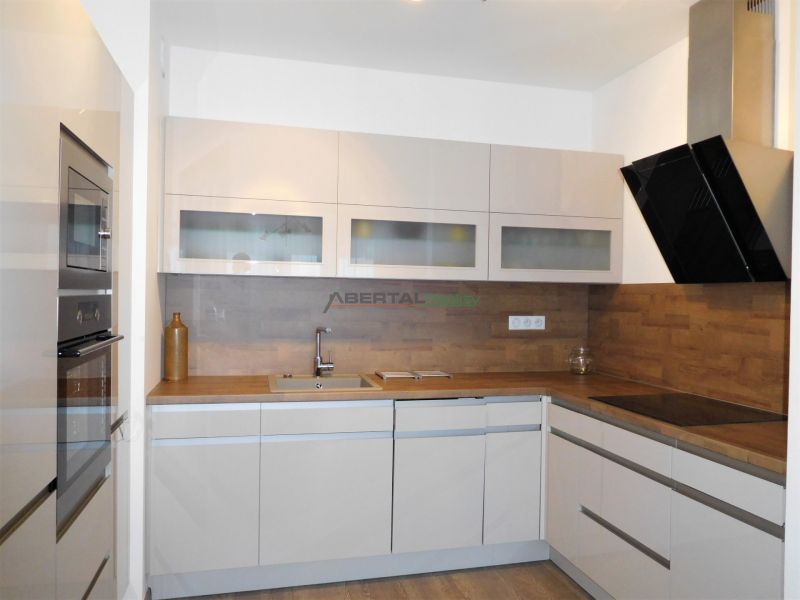 A kitchen in a 2-room apartment with white cabinets and a wood-patterned floor.