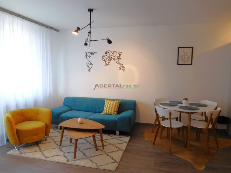 Living room in a two-room apartment with a sofa, armchair, coffee table, and dining table.