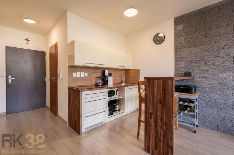 The kitchen of a 2-room apartment with a wooden decor floor and cooking equipment.