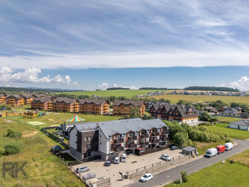 Veľká Lomnica, Futbalová: apartment complexes surrounded by greenery, cars, and a children's playground.