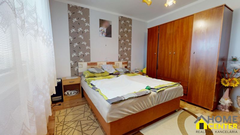 A bedroom in a 3-room apartment with floral wallpaper and a wooden decor floor.