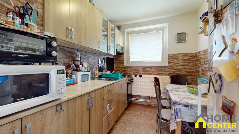 A kitchen in a 3-room apartment with a kitchen unit, microwave, and dining table.