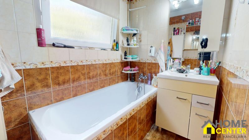 A bathroom with a shower, sink, and tiles in a 3-room apartment.
