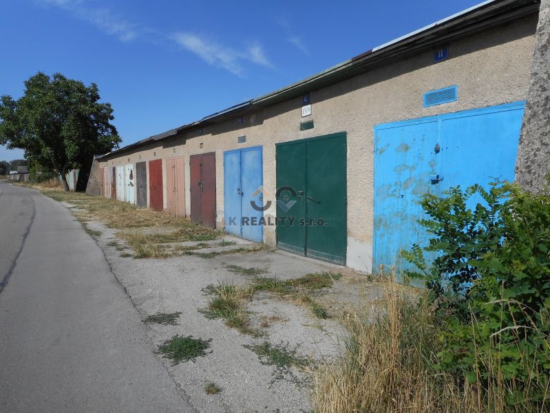 Garages on Ľudovíta Stárka Street in Trenčín with doors of various colors and trees.