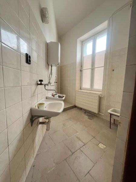 Bathroom in production premises with sinks and a boiler, tiled floor.