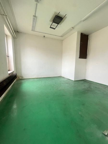 The interior of a manufacturing space with white walls and a green floor.