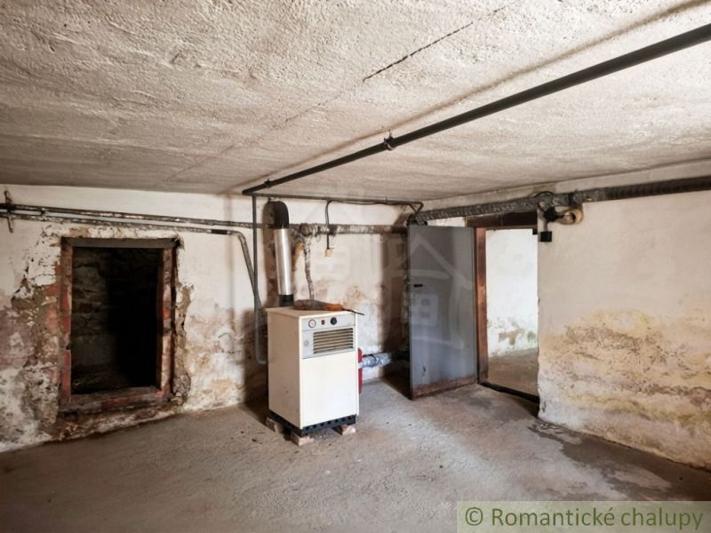 Basement spaces with a boiler in a family house. The walls are damp and peeling.