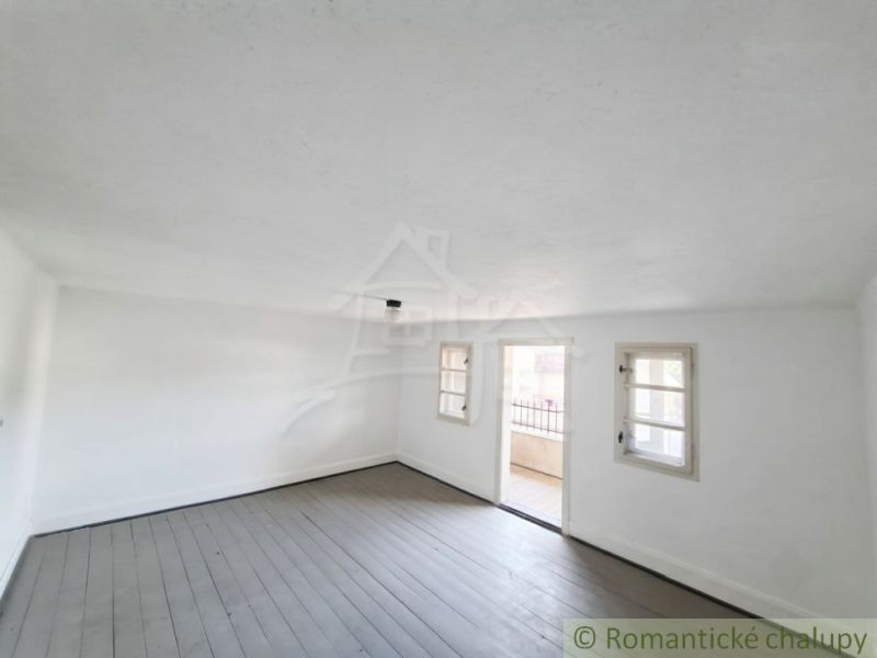 A spacious room with a wood-patterned floor in a family house with white walls.