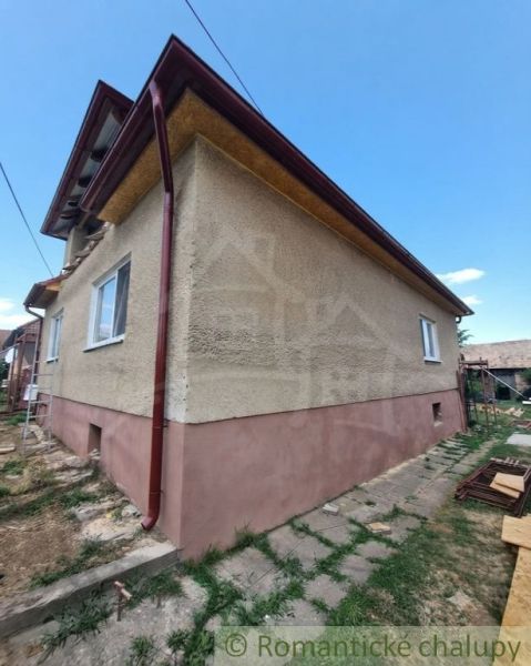 A family house in Ružiná with windows and a brown roof in a landscaped garden.