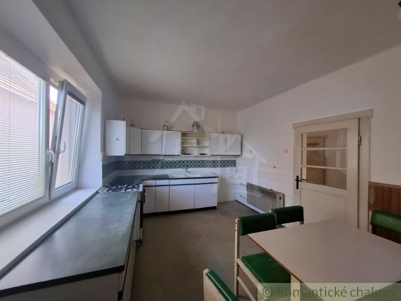 A kitchen in a family house with a dining table, white cabinets, and a large window.