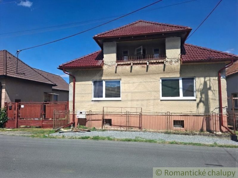 A family house in Ružiná with a brown roof and gate, next to the road.