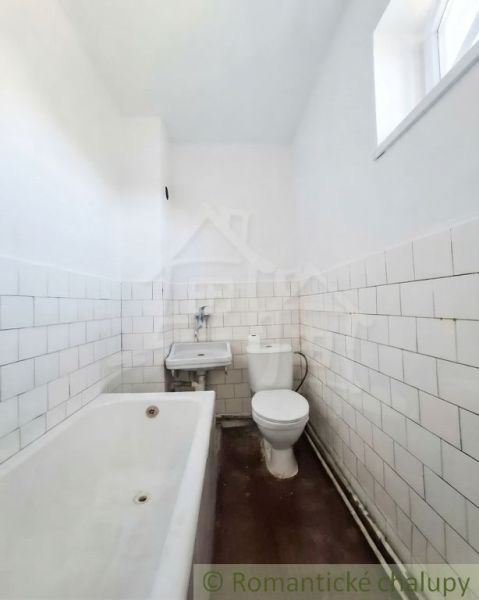 A bathroom in a family house with a bathtub, a sink, and a toilet, with light tiles.