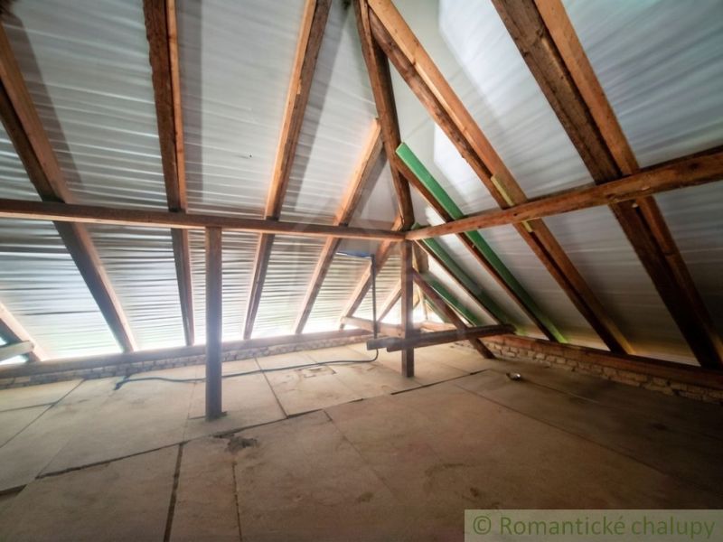 The attic of a family house with wooden beams and light penetrating through the roof.