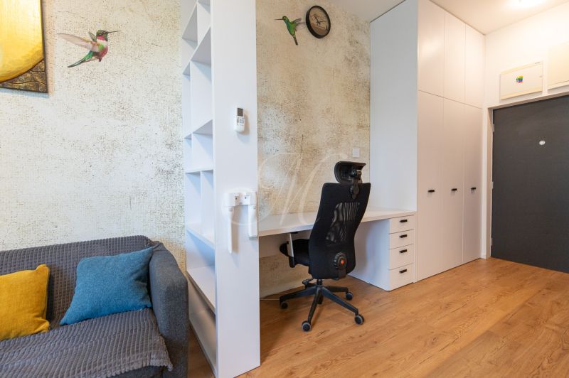 A workspace in a studio apartment with a wood-patterned floor and a decorative wall.