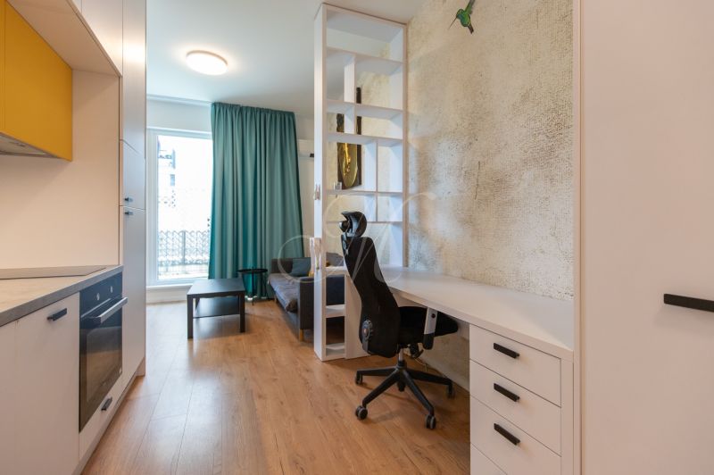 Interior of a 1-room apartment with a table, chair, and floor with wooden decor.