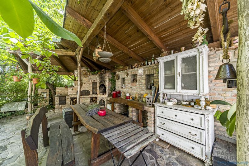 Rustic terrace with wooden furniture and a tiled stove in a family house.