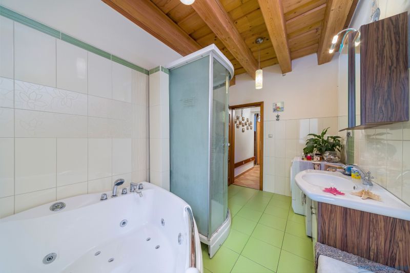 Bathroom with a bathtub, shower corner, and wooden ceiling in a family house.