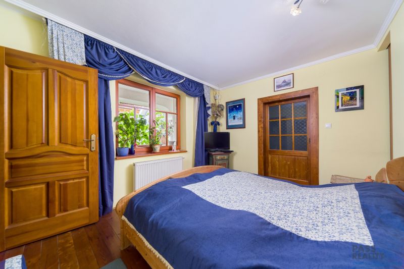 Bedroom with curtains, wooden doors, and a wooden decor floor in a family house.