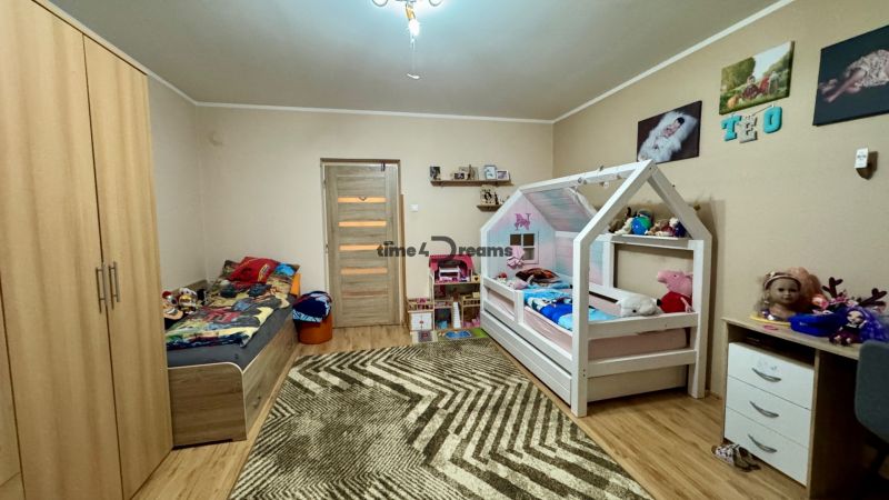 Children's room with wood-decor flooring, beds, and toys in a family house.