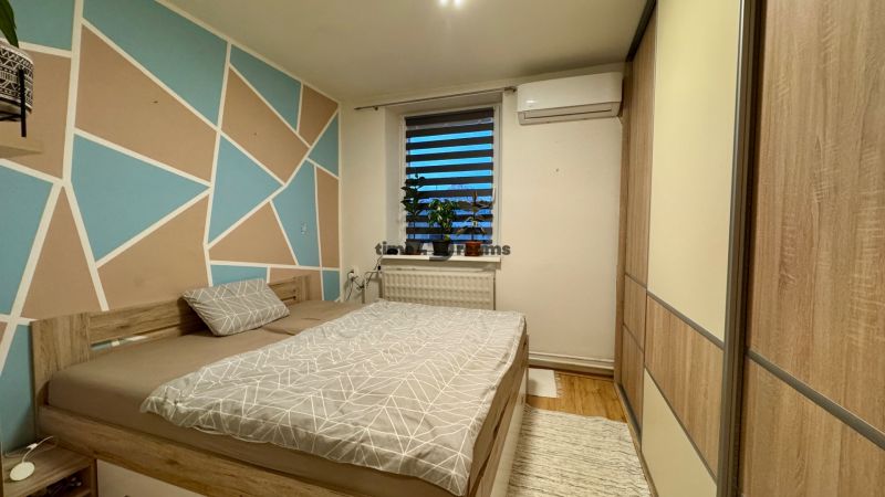 Bedroom in a family house with a colored wall and a bed, floor with a wooden decor.