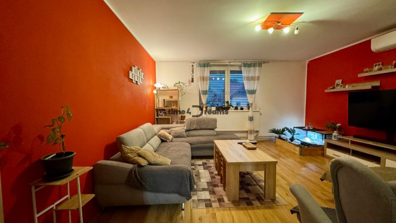 Living room of a family house with red walls, a sofa, and a wooden decor floor.