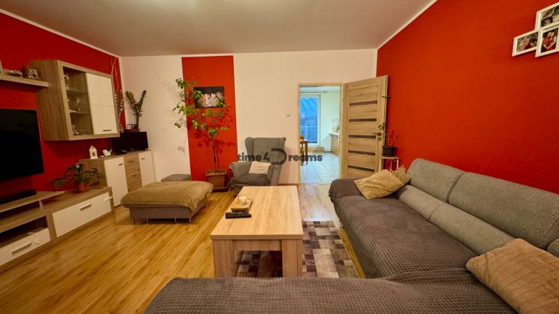Living room with wood-patterned flooring, gray sofa, and red walls in a family house.