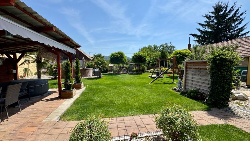 The garden of a family house in Čakajovce with a gazebo, lawn, and children's playground.