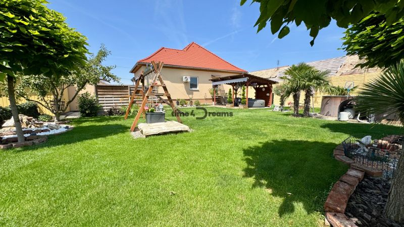 The garden of a family house in Čakajovce with a lawn, a gazebo, and a children's playground.