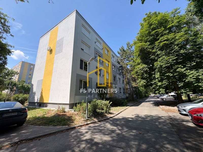 The exterior of the apartment building on Rákóczi Street in Komárno surrounded by trees and cars.